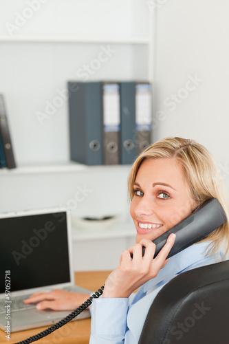 Photo: Blonde businesswoman smiling into camera while on the phone Blonde businesswoman smiling into camera while on the phone