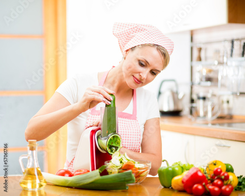 Photo: woman cutting vegetables with device at the kitchen table woman cutting vegetables with device at the kitchen table