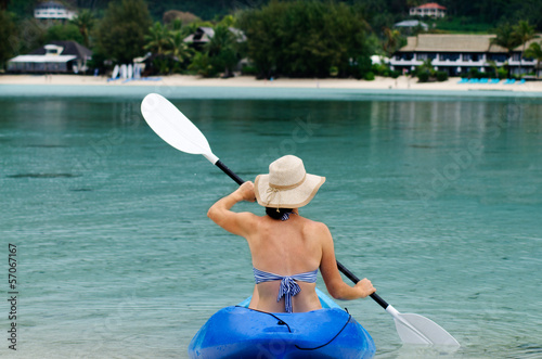 Photo: Young caucasian woman kayaking over turquoise water Young caucasian woman kayaking over turquoise water