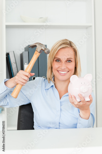 Photo: Happy woman wanting to destroy her piggy bank Happy woman wanting to destroy her piggy bank