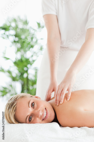Photo: Good looking woman relaxing on a lounger during massage Good looking woman relaxing on a lounger during massage