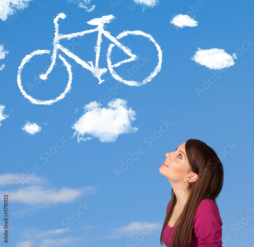Photo: Young girl looking at bicycle clouds on blue sky Young girl looking at bicycle clouds on blue sky
