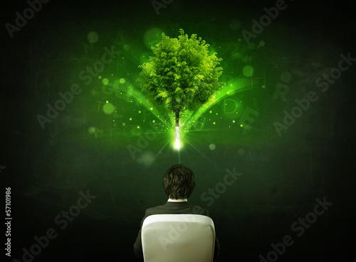 Photo: Businessman in chair sitting in front of a glowing tree Businessman in chair sitting in front of a glowing tree