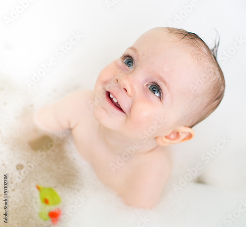 Photo: smiling baby girl taking bath and playing with toys smiling baby girl taking bath and playing with toys