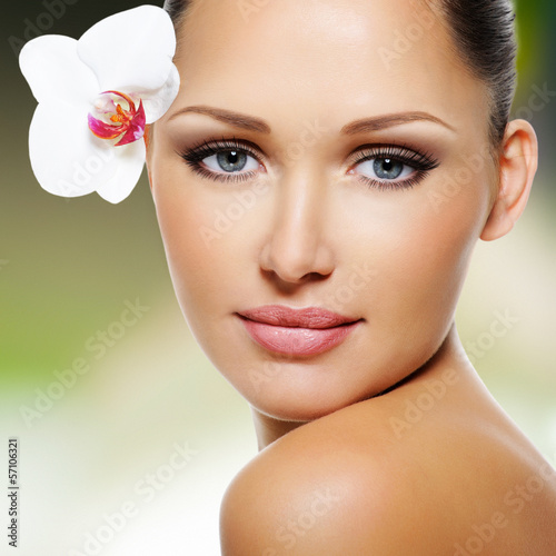 Photo: Face of beautiful woman with a white orchid flower Face of beautiful woman with a white orchid flower