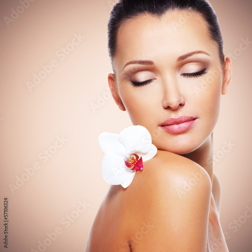 Photo: Face of beautiful woman with a white orchid flower Face of beautiful woman with a white orchid flower