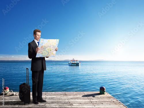 Photo: Business man standing on pier with map in hands Business man standing on pier with map in hands