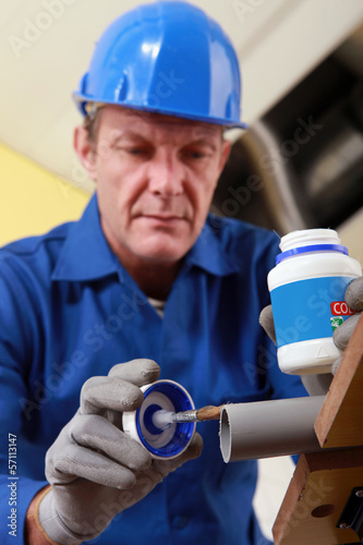 Photo: Plumber gluing grey plastic pipe Plumber gluing grey plastic pipe
