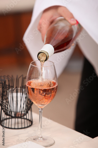 Photo: Waiter's hand pouring a bottle of rose wine Waiter's hand pouring a bottle of rose wine