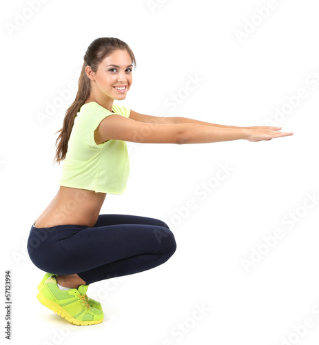 Photo: Beautiful young girl doing exercises isolated on white Beautiful young girl doing exercises isolated on white