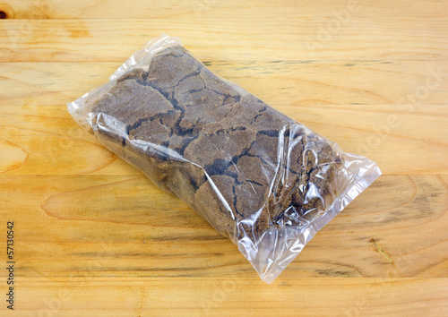 Photo: Plastic wrapped dark brown sugar on a wood cutting board Plastic wrapped dark brown sugar on a wood cutting board