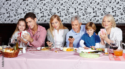 Photo: Familie schaut auf ihre Smartphones Familie schaut auf ihre Smartphones