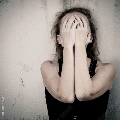 Photo: one sad woman sitting on the floor near a wall and holding her h one sad woman sitting on the floor near a wall and holding her h