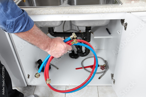 Photo: Hands of Plumber with a wrench. Hands of Plumber with a wrench.