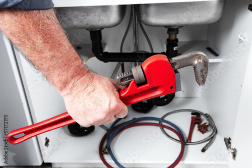 Photo: Hands of Plumber with a wrench. Hands of Plumber with a wrench.