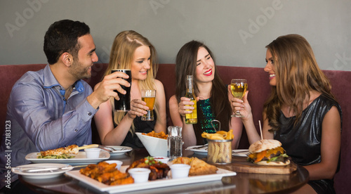 Photo: Happy friends sitting together having dinner Happy friends sitting together having dinner
