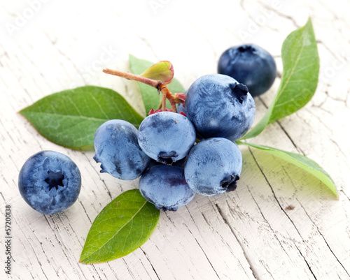 Photo: Blueberries with leaves on a wooden table. Blueberries with leaves on a wooden table.