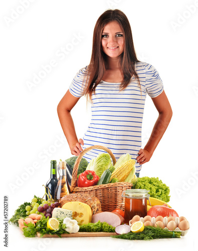 Photo: Young woman with assorted grocery products isolated on white Young woman with assorted grocery products isolated on white