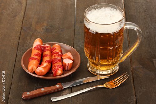 Photo: Beer and grilled sausages on wooden background Beer and grilled sausages on wooden background