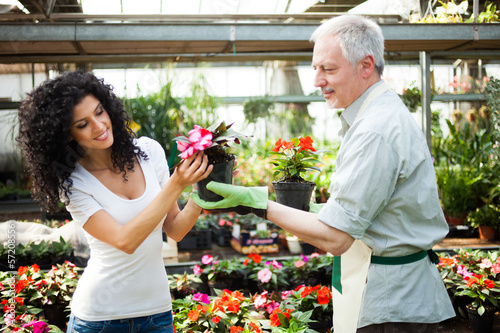Photo: Shop assistant giving a flower pot to a customer Shop assistant giving a flower pot to a customer