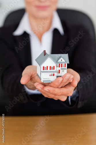 Photo: Portrait of feminine hands holding a miniature house Portrait of feminine hands holding a miniature house