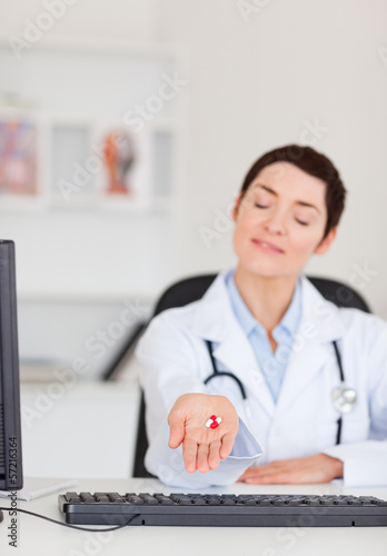 Photo: Portrait of a young female doctor showing pills Portrait of a young female doctor showing pills