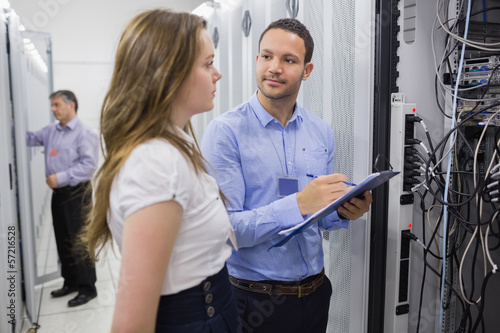 Photo: Two people checking servers with one holding clipboard Two people checking servers with one holding clipboard