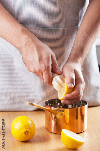 Photo: man squeezing lemon into a copper pot man squeezing lemon into a copper pot