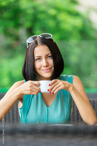 Photo: Girl wearing blue dress and sunglasses drinks tea Girl wearing blue dress and sunglasses drinks tea