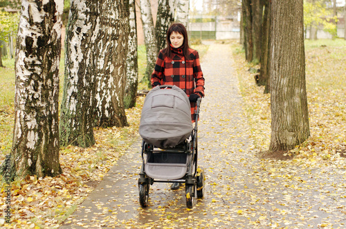 Photo: woman walking in autumn park with baby buggy woman walking in autumn park with baby buggy