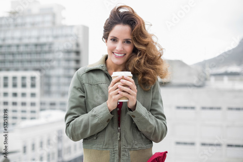 Photo: Smiling gorgeous brunette in winter fashion holding disposable c Smiling gorgeous brunette in winter fashion holding disposable c
