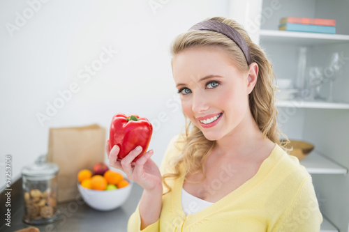 Photo: Smiling cute blonde holding a red pepper Smiling cute blonde holding a red pepper
