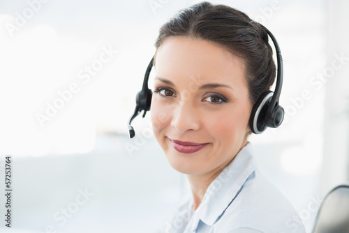 Photo: Content stylish brunette operator smiling and looking at camera Content stylish brunette operator smiling and looking at camera