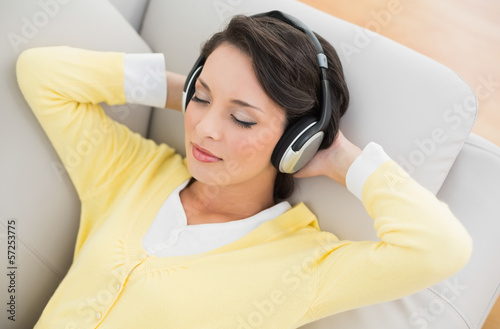 Photo: Relaxed casual brunette in yellow cardigan listening to music wi Relaxed casual brunette in yellow cardigan listening to music wi