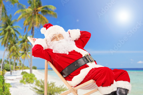 Photo: Relaxed Santa Claus sitting on a chair, on a beach, enjoying Relaxed Santa Claus sitting on a chair, on a beach, enjoying