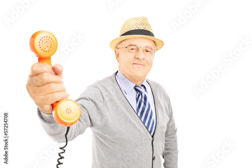 Photo: Senior gentleman giving a telephone to somebody to talk Senior gentleman giving a telephone to somebody to talk