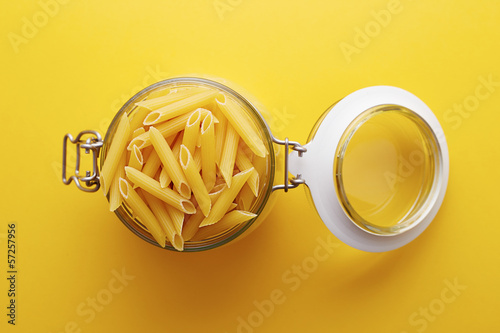 Photo: Raw penne rigate pasta on a glass jar Raw penne rigate pasta on a glass jar