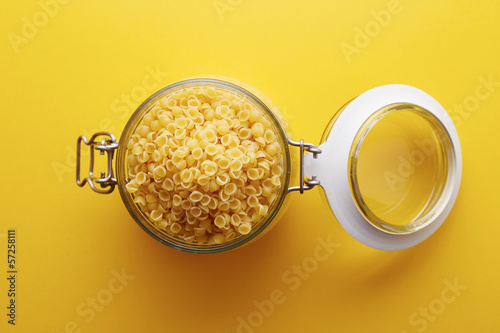 Photo: Raw conchigliette pasta on a glass jar Raw conchigliette pasta on a glass jar