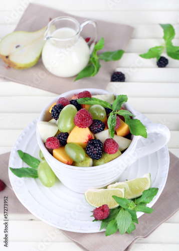 Photo: Fruit salad in cup on wooden table Fruit salad in cup on wooden table