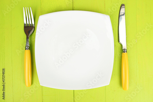 Photo: Plate and cutlery on wooden table close-up Plate and cutlery on wooden table close-up
