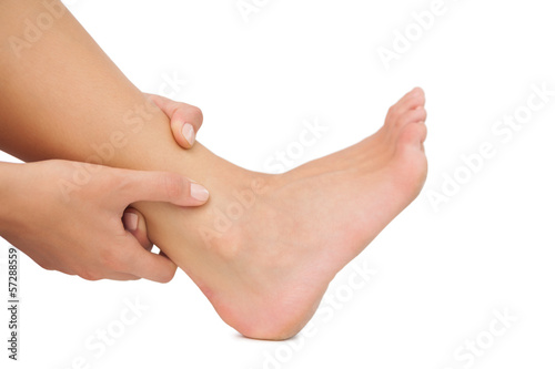 Photo: Young woman sitting on ground touching her injured foot Young woman sitting on ground touching her injured foot