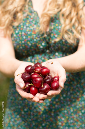 Photo: Close up of a blonde woman holding some cherries Close up of a blonde woman holding some cherries