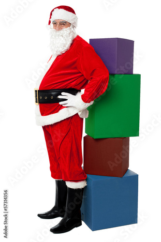 Photo: Santa standing beside pile of xmas gifts Santa standing beside pile of xmas gifts