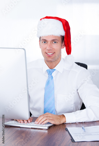Photo: Businessman Wearing Santa Hat Using Computer Businessman Wearing Santa Hat Using Computer