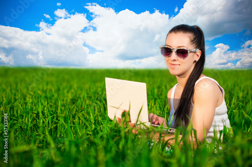 Photo: woman in a green field with a laptop. summer woman in a green field with a laptop. summer