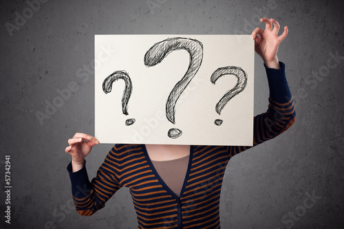 Photo: Woman holding paper with drawed question marks in front of her h Woman holding paper with drawed question marks in front of her h