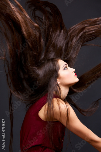 Photo: Fashion portrait of beautiful woman with long hair on gray Fashion portrait of beautiful woman with long hair on gray