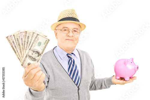 Photo: Mature gentleman holding a piggy bank and US dollars Mature gentleman holding a piggy bank and US dollars
