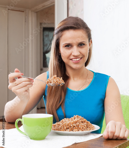 Photo: woman eats buckwheat at home interior woman eats buckwheat at home interior