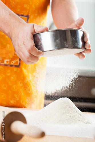 Photo: mans hands sifting flour through a sieve for baking mans hands sifting flour through a sieve for baking